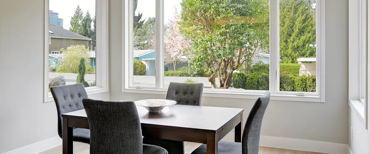 Modern dining area with clear view through new WINDOW REPLACEMENT, showcasing outdoor greenery.