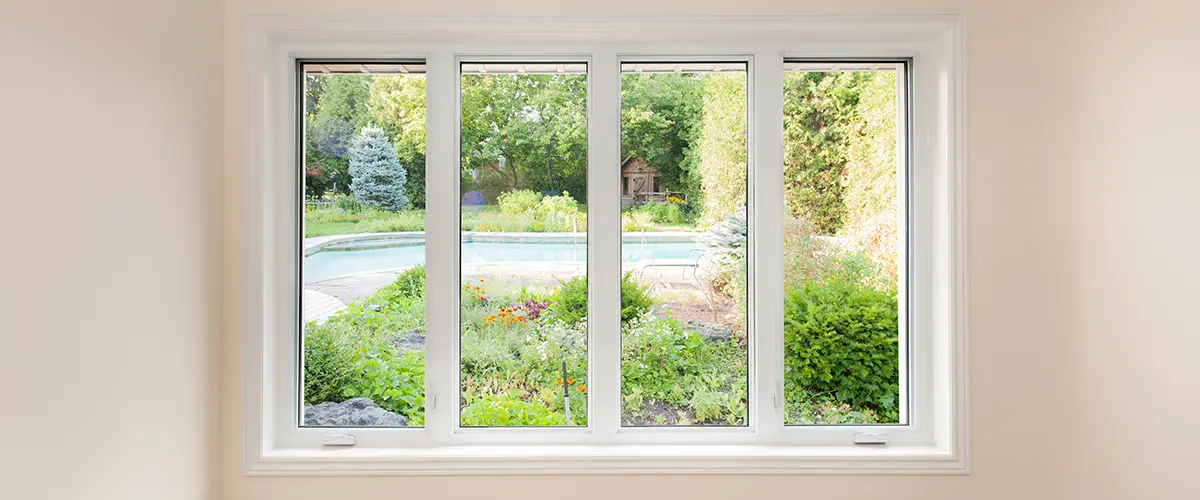 Bright garden view from white casement window, lush greenery and pool.