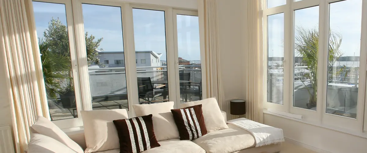 Interior of modern living room with beige corner suite. Composite VS Vinyl Windows