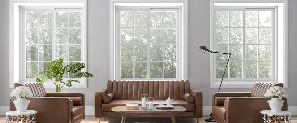 Modern living room with large windows in Brentwood, brown leather sofas, a coffee table, and indoor plants.