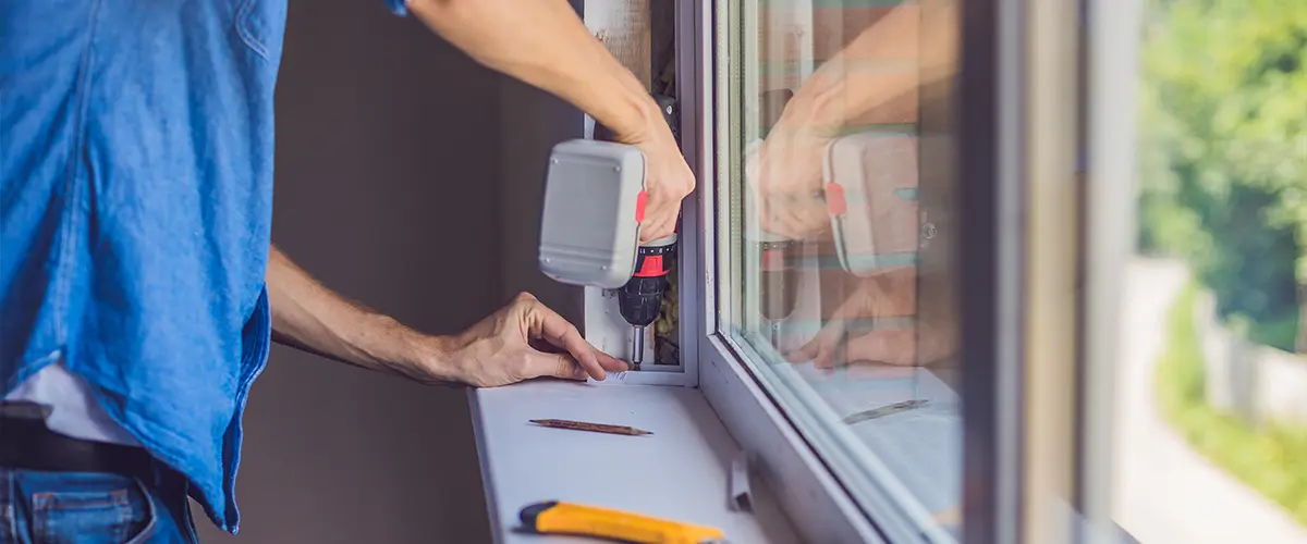 Close-up of a worker using a drill to install a window, emphasizing professional window installation services in Cambridge Farms, Gallatin, TN.