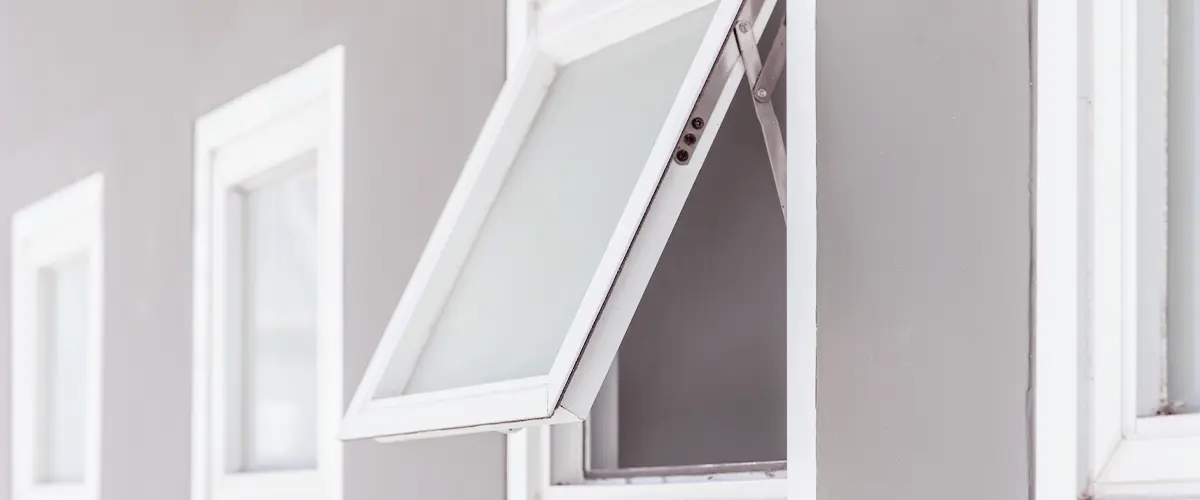 Open awning window on a modern building exterior with white frames