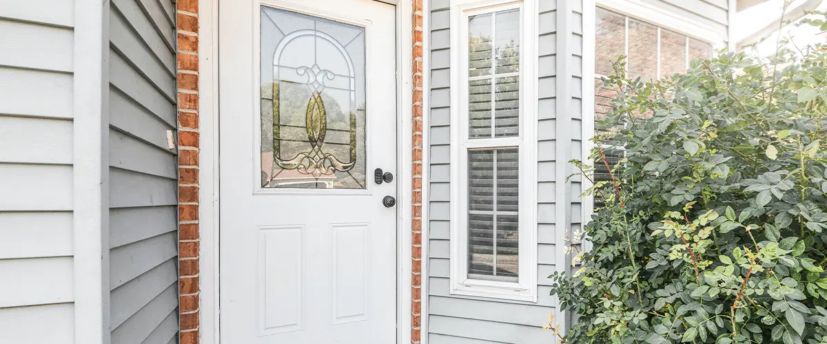 Best exterior doors for cold weather, close-up of a vinyl door on a modern home with decorative glass panel