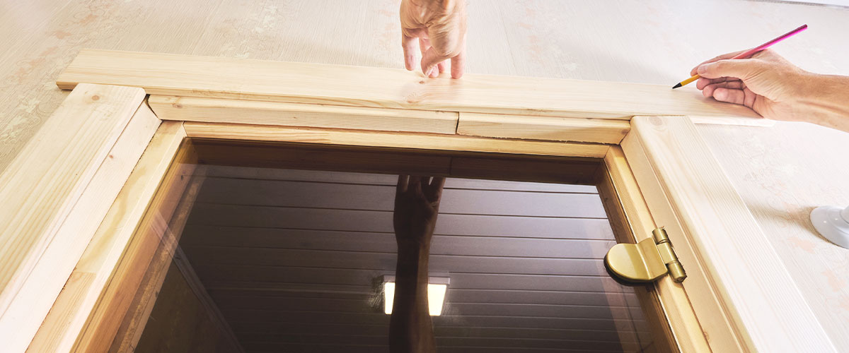 Installation of a wooden door with brickmold, showing precise measurements being taken during the process