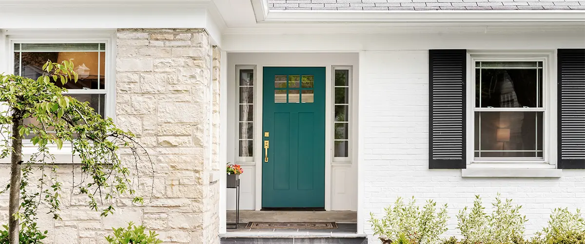 Exterior of a house with a teal front door, surrounded by well-maintained landscaping, including shrubs and a pathway