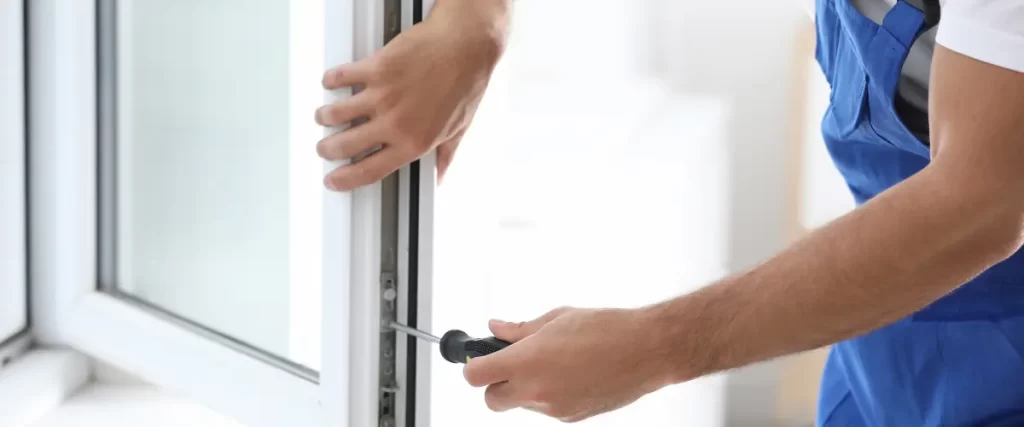 Hands using a small tool to adjust or install the locking mechanism of a window.