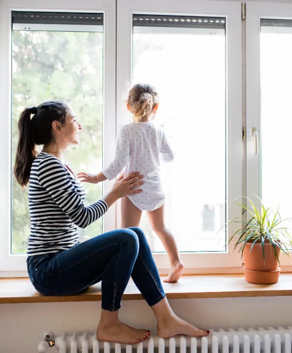 A young mother and her child looking out the window and smiling
