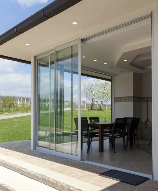 a modern residential space with large aluminum-framed sliding glass doors that open onto an outdoor patio area