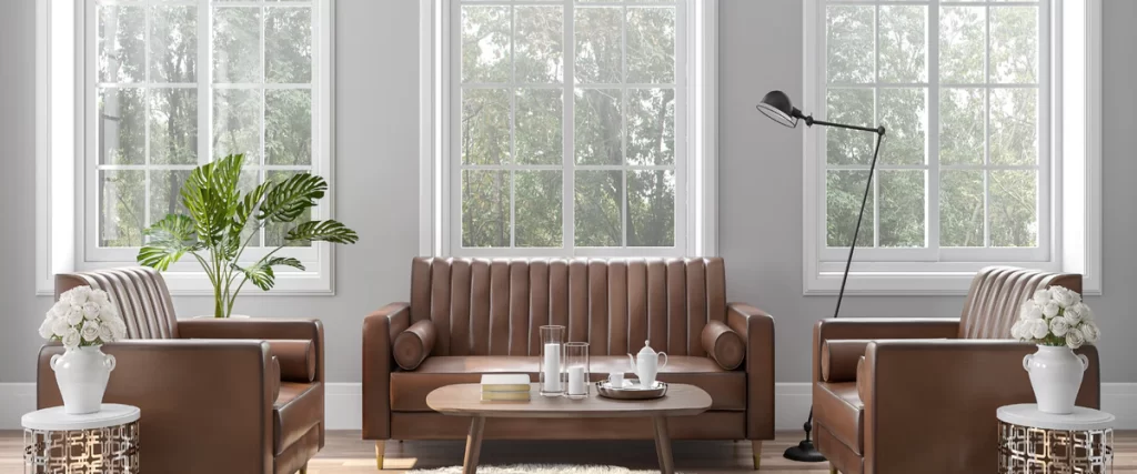 A stylish living room interior showcasing new windows behind a brown leather sofa with a wooden coffee table and indoor plants.