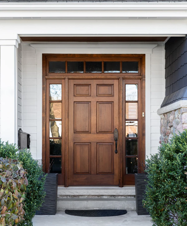 A beautifully stained classic wooden front door with glass sidelights and a transom window, showcasing a professional door installation in Nashville, TN.