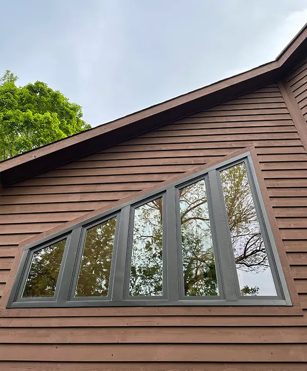 Modern angled replacement windows installed on contemporary home with wood siding