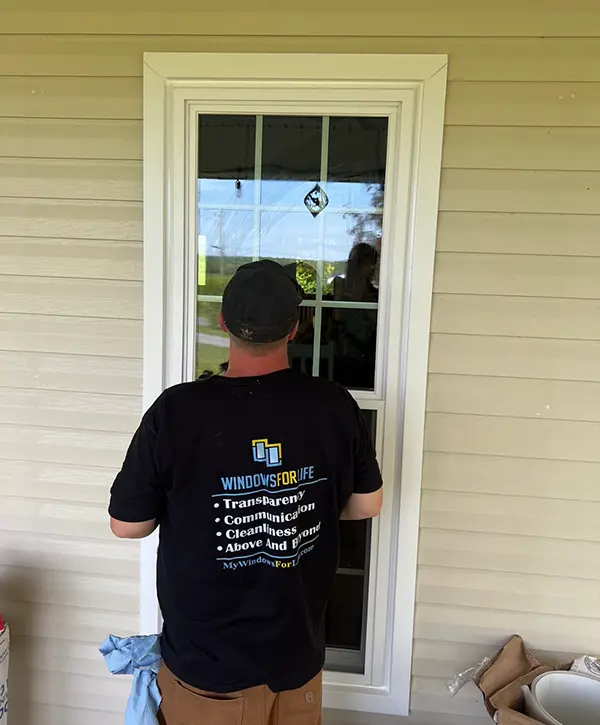 Window installer fitting new vinyl replacement window on residential home exterior