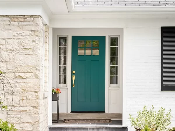 Exterior of a house with a teal front door, surrounded by well-maintained landscaping, including shrubs and a pathway